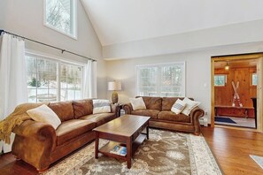 Ein Wohnzimmer mit zwei braunen Ledersofas, einem Holztisch und einem gemusterten Teppich.