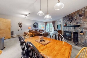 Ein Essbereich mit Holztisch und Stühlen, einem Kamin und Pendelleuchten.