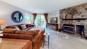 Ein Wohnzimmer mit Sofa, Fernseher, Kamin und Blick ins Freie.