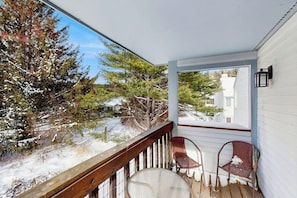 Eine überdachte Veranda mit Blick auf eine verschneite Landschaft und Bäume.