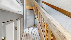 Una stretta scala in legno con corrimano, che conduce a una porta in cima.