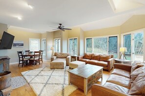 A spacious living room with a fireplace, leather sofas, a wooden coffee table, and large windows. - Ski-in/out home with a hot tub, fireplace, cable & golf nearby (Ludlow)