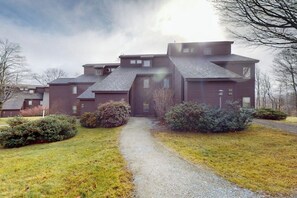 A multi-story house with a gravel driveway and surrounding greenery. - Ski-in/out Condo on Bull Run Trail with fireplace, & full kitchen (Ludlow)