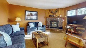 Una sala de estar con dos sofás, una mesa de centro, una chimenea y un televisor.