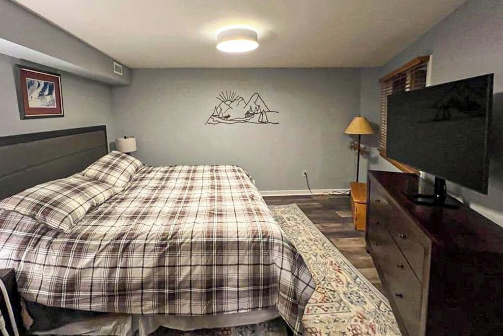 Une chambre à coucher comprenant un lit, une télévision, une commode, une lampe et une œuvre d’art murale.