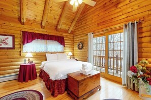 A wooden cabin bedroom with a bed, bedside tables, a window with curtains, and a wooden ceiling. - Beautiful home near lifts with wood-burning fireplace, mountain views & cable (Ludlow)