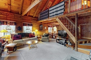 A log cabin interior with a sofa, armchairs, a television, a staircase, and a dog. - Beautiful home near lifts with wood-burning fireplace, mountain views & cable (Ludlow)