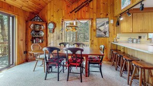 Un interior de madera con una mesa de comedor, sillas, una araña y una pared decorada con motivos deportivos.