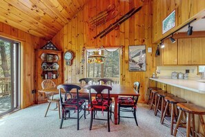 A wooden interior with a dining table, chairs, a chandelier, and a sports-themed wall. - Inviting Okemo ski mountain home, two house walk to ski slope! (Ludlow)