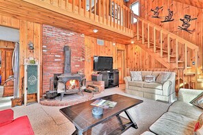 A log cabin interior with a fireplace, sofa, and a staircase. - Inviting Okemo ski mountain home, two house walk to ski slope! (Ludlow)