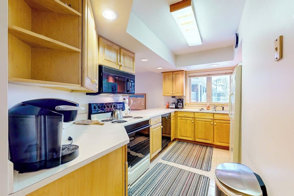 A kitchen with wooden cabinets, a built-in microwave, a stove, and a coffee maker.