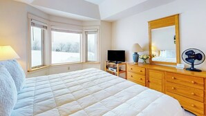 Un dormitorio con una cama grande, televisión, cómoda y espejo.
