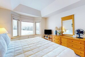 Ein Schlafzimmer mit einem großen Bett, einem Fernseher, einer Kommode und einem Spiegel.