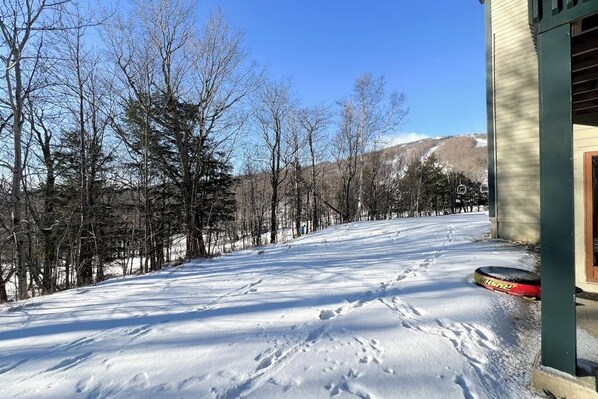 A snow-covered landscape with a building on the right, a ski lift in the background, and bare trees. - Winterplace ground-floor ski-in/ski-out condo on the Lift Line trail (Ludlow)