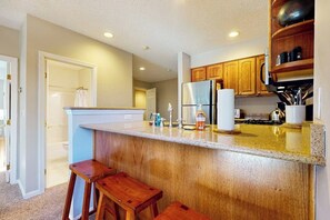 Eine Küche mit Holzschränken, einem Edelstahlkühlschrank und einer Arbeitsplatte aus Granit.