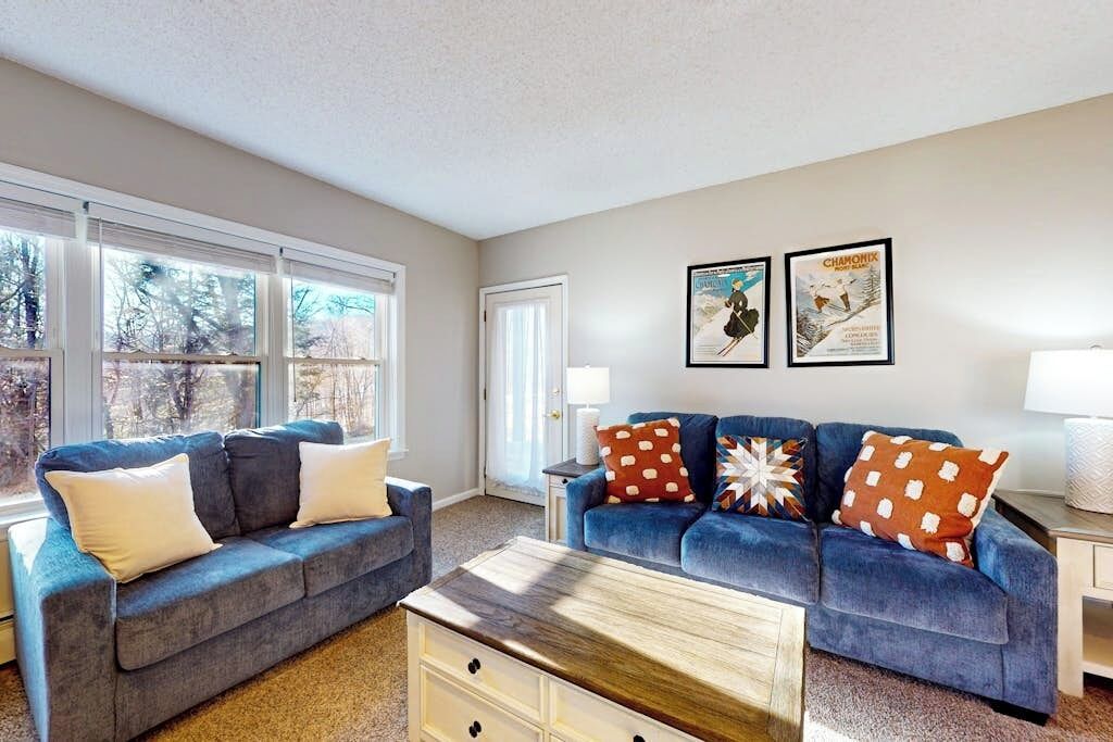 A living room with two sofas, a coffee table, and a door leading outside.