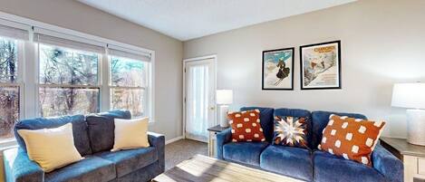 A living room with two sofas, a coffee table, and a door leading outside.