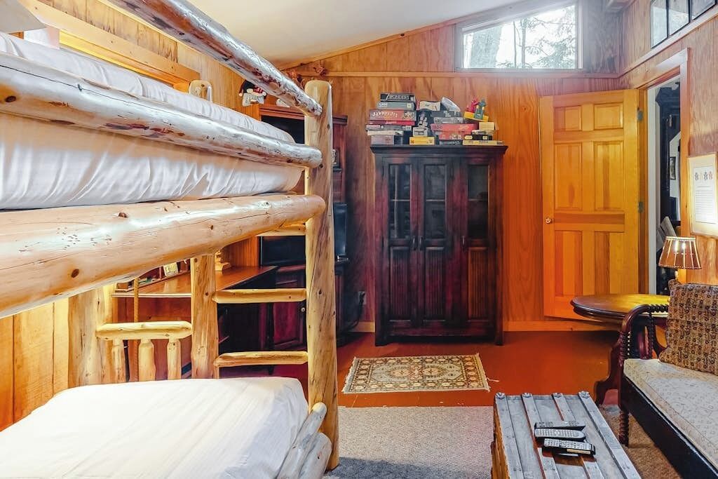 Ein Holzinnenraum mit Etagenbetten, einem Schrank, einer Couch und einem kleinen Tisch.
