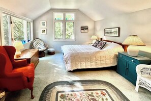 A bedroom with a bed, two bedside tables, a chair, a small table, and a window. - Spacious Home w/Seasonal Lake View, Washer/Dryer & Cable (Ludlow)