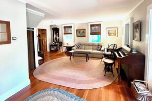 A living room with a sofa, coffee table, and a piano. - Spacious Home w/Seasonal Lake View, Washer/Dryer & Cable (Ludlow)
