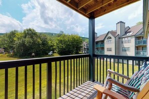 A balcony with a view of a residential area, a wooden table, and a chair. - Ski-in/out condo with fireplace, hot tubs. pool, tennis & washer/dryer (Ludlow)