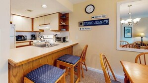 Una cocina compacta con armarios de madera, un lavamanos y una zona de comedor con mesa y sillas.