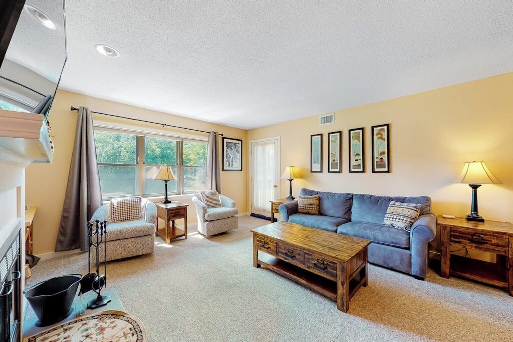 A living room with a sofa, armchairs, a coffee table, and a fireplace.