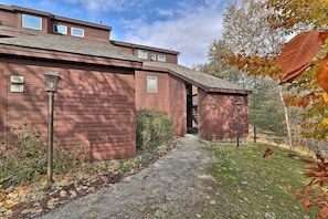 Ein rotes Holzgebäude mit Garage, einem Weg zum Eingang und einem kleinen Garten.