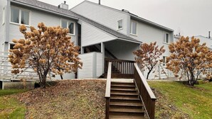 Une maison à deux étages avec un escalier en bois menant à un porche.