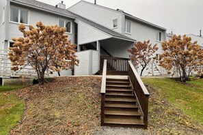 Una casa de dos pisos con una escalera de madera que sube a un porche.