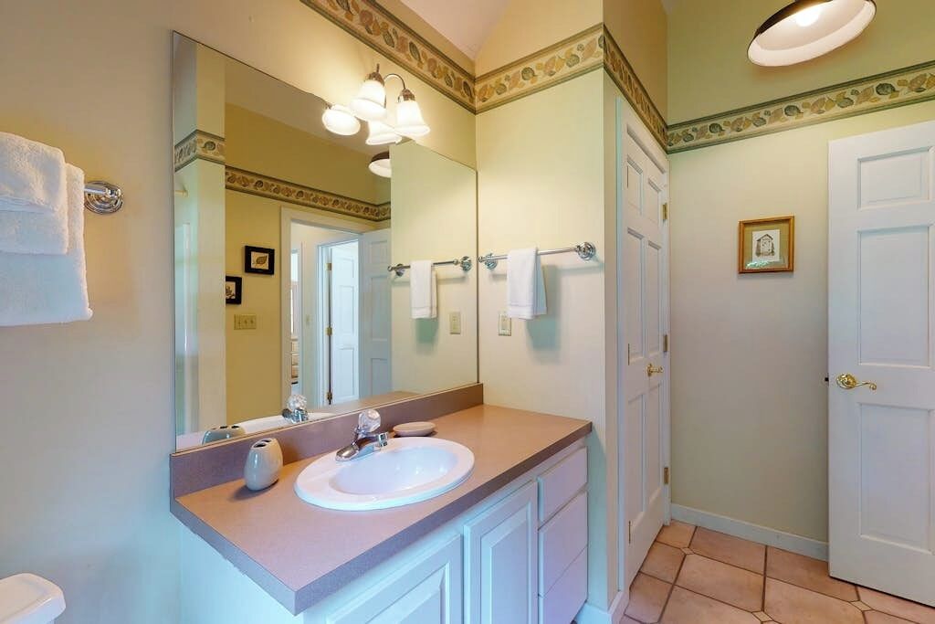 Un baño con un espejo grande, un lavabo y un inodoro.