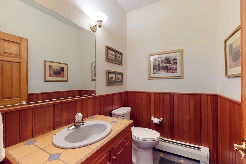 Une salle de bain avec un meuble-lavabo en bois, un évier, des toilettes et des tableaux encadrés accrochés aux murs.