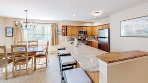 A modern kitchen with wooden cabinets, a granite countertop, and stainless steel appliances. - Condo near ski trail with fireplace, hot tub, pool, tennis & washer/dryer (Ludlow)