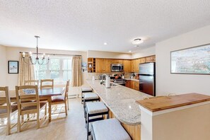 A modern kitchen with wooden cabinets, a granite countertop, and stainless steel appliances. - Condo near ski trail with fireplace, hot tub, pool, tennis & washer/dryer (Ludlow)