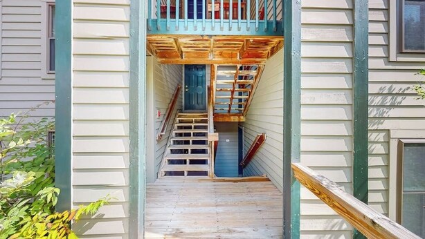 A narrow wooden staircase leading to a blue door, surrounded by light-colored siding and a green railing. - Condo near ski trail with fireplace, hot tub, pool, tennis & washer/dryer (Ludlow)