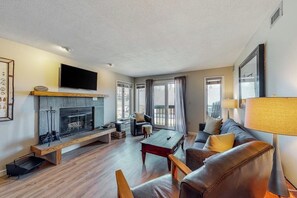 Ein modernes Wohnzimmer mit Kamin, Sofa, Couchtisch und einem an der Wand montierten Fernseher.