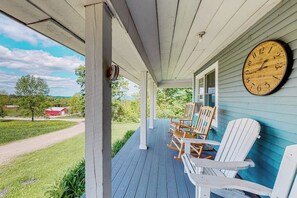 A porch with a clock, Adirondack chairs, and a view of a rural landscape. - Secluded escape on rolling acreage with hot tub, deck, gas grill, & fast WiFi (Ludlow)