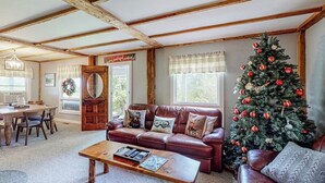 A cozy living room with a leather sofa, a coffee table, a Christmas tree, and a wooden ceiling. - Secluded escape on rolling acreage with hot tub, deck, gas grill, & fast WiFi (Ludlow)