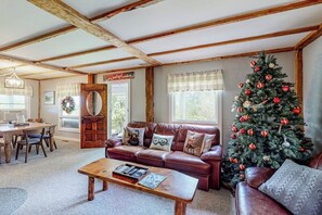 A cozy living room with a leather sofa, a coffee table, a Christmas tree, and a wooden ceiling. - Secluded escape on rolling acreage with hot tub, deck, gas grill, & fast WiFi (Ludlow)