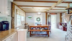 A cozy kitchen with a wooden table, chairs, and a stone fireplace. - Secluded escape on rolling acreage with hot tub, deck, gas grill, & fast WiFi (Ludlow)