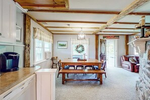 A cozy kitchen with a wooden table, chairs, and a stone fireplace. - Secluded escape on rolling acreage with hot tub, deck, gas grill, & fast WiFi (Ludlow)