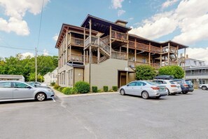 Ein mehrstöckiges Gebäude mit Balkon, Parkplatz und Autos.