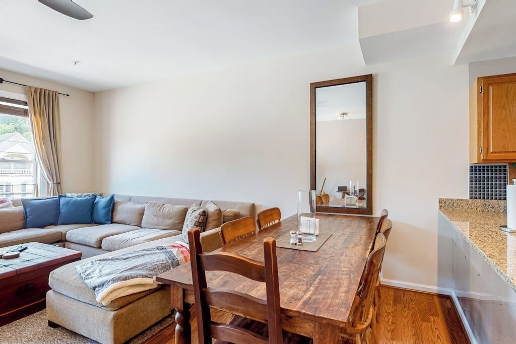 A living room with a sofa, a wooden dining table, and a kitchen area with cabinets.