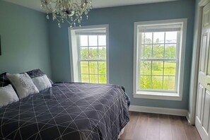 Ein Schlafzimmer mit einem Bett, zwei Fenstern und einer Chandelieber.