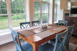 Ein Essbereich mit Holztisch, blauen Stühlen und großen Fenstern.