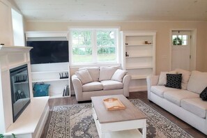 Ein Wohnzimmer mit Kamin, zwei Sofas, einem Couchtisch und einem großen Fenster.