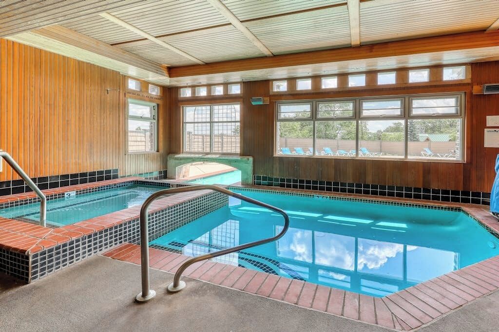 Ein Poolbereich mit gefliesten Stufen, einem Metallgeländer und großen Fenstern.