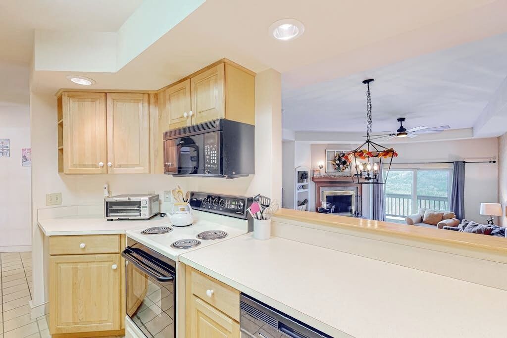 A kitchen with wooden cabinets, a microwave, a stove, and a chandelier.