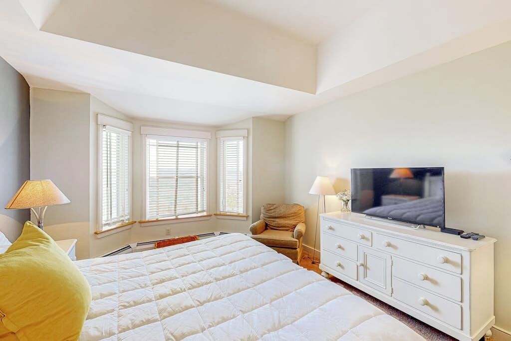 A bedroom with a large bed, a TV, a dresser, and a chair.