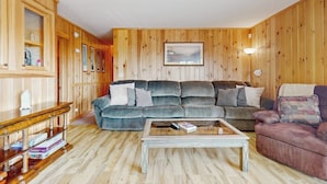 Ein Zimmer mit Holzwänden, einer Couch, einem Couchtisch und einer Lampe.